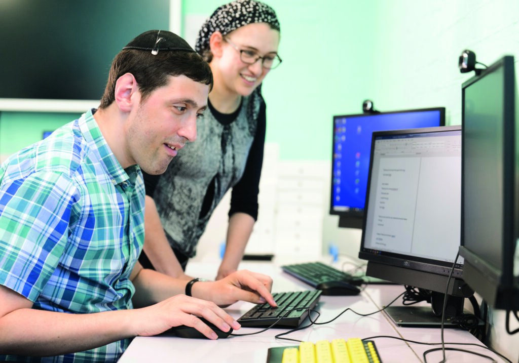 Employee receiving support with computer-based work during a supported employment and skills development session.